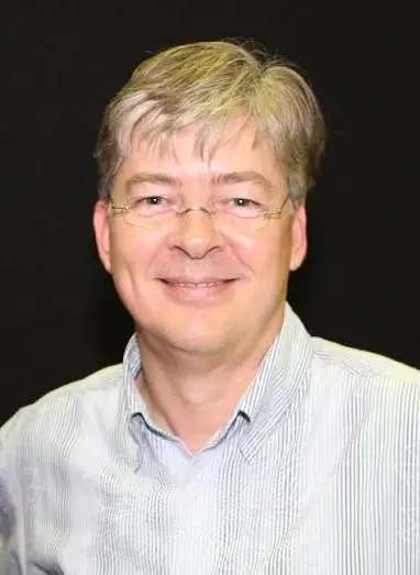 Portrait of Anders Hejlsberg before an interface evoking Turbo Pascal, C#, and TypeScript
