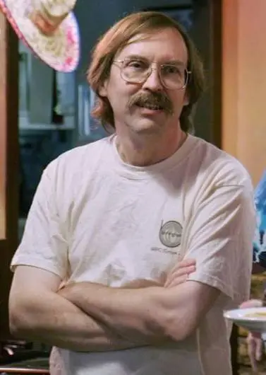 Portrait of Larry Wall before a terminal evoking Perl, Unix, and regular expressions